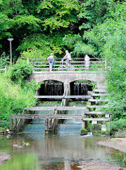 Brücke über die Krückau bei der Barmstedter Schlossinsel - Spaziergänger + Radfahrer auf der Steinbrücke - Bäume auf der Schlossinsel.