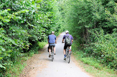Radweg am Rande des Heidkoppelmoors in Hoiesbüttel / Ammersbek - zwei Radfahrer bei einer Radtour durch das Naturschutzgebiet.