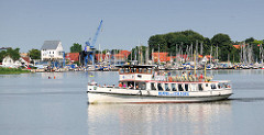 Fahrgastschiff Wappen von Schleswig auf der Schlei bei - im Hintergrund der Sportboothafen, ehem. Speichergebäude und Hafenkran vom Hafen der Stadt Schleswig.