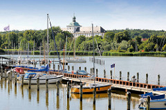 Sportboothafen an der Schlei in Schleswig - im Hintergrund das Gottorfer Schloss zwischen Bäumen.