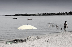 Badestrand an der Schlei in Schleswig - Sandstrand beim Neubaugebiet Auf der Freiheit. Badende Familien im Wasser - Sonnenschirm im Sand; Boote auf der Schlei.