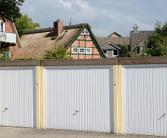 Reetdachkate - Wohnhaus mit Reet gedeckt, Fachwerkhaus - Norderstedt / Garstedt. Garagen mit Metalltor im Vordergrund.