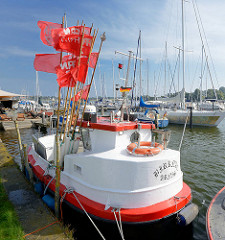 Fischereiboot im Hafen von Arnis, rote Positionsfahnen flattern im Wind - im Hintergrund ein Sportboothafen - Marina an der Schlei.