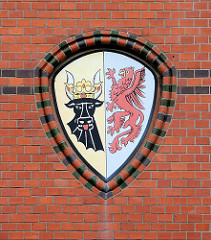 Wappen von Mecklenburg Vorpommern an der Ziegelfassade / Backsteinfassade des historischen Postgebäudes in Wismar. Schwarzer Stierkopf - roter Greif.