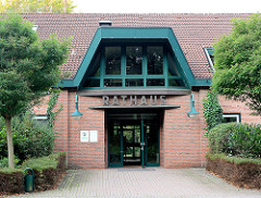 Eingang Rathaus Gemeinde Großhansdorf - Architekturstil der 1970er Jahre; grün abgesetzte Metallfensterrahmen - Lampen; Schriftzug Rathaus über der Eingangstür.