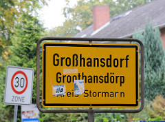Ortsschild Großhansdorf - Plattdeutsch Groothansdörp, Kreis Stormarn; gelber Grund mit schwarzer Schrift.