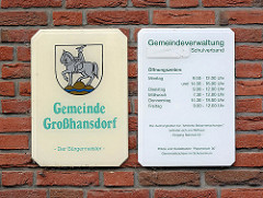 Schild Gemeinde Großhansdorf mit Wappen - silberner Reiter auf goldenem Dreiberg - Öffnungszeiten Gemeindeverwaltung.