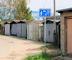 Schild Spielstrasse in Wolgast - Garagen und Schuppen; im Hintergrund ein Werftgebäude der Peene Werft.