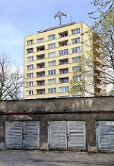 Hochhaus mit gelber Fassade, Wohnhaus - alte Garagentore aus Holz im Vordergrund / alt + neu, Architektur.