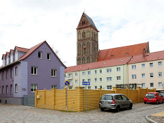 Etagenhaus mit violetter Fassade - mehrstöckige Wohnblocks - Marienkirche; Backsteingotik aus dem 13. Jahrhundert.