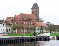 Blick über das Hafenbecken in Anklam - mehrstöckige Wohngebäude und der Kirchturm der Marienkirche - die dreischiffige Hallenkriche der Backsteingotik stammt aus dem 13. Jahrhundert.