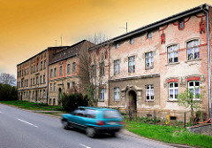 Alte Wohnblocks - renovierungsbedürftige, verfallene Wohnhäuser - Strasse mit fahrendem Auto; Bilder aus der Hansestadt Anklam.