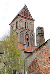 Kirchturm der gotischen Marienkirche in Anklam - unverputzte Ziegelwand, Schornstein.