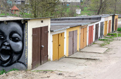 Garagen mit farbigen Holztüren - lachendes Kind als Graffiti - Bilder aus Lidzbark Warmiński / Heilsberg.