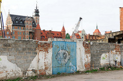 Ziegelmauer, Metalltor mit Graffiti auf der Danziger Speicherinsel - im Hintergrund die Altstadt von Danzig.