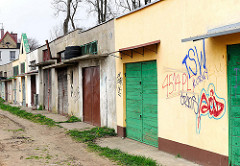 Garagen mit unterschiedlich gestalteten Türen, Wand mit Grafitti - Fotos aus Darłowo / Rügenwalde, Polen.