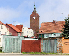 Garagentore / Schuppen; Wohnhäuser und Kirchturm der gotischen Backsteinarchitektur der Marienkirche in Darłowo / Rügenwalde, Polen.