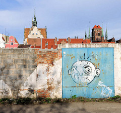 Ziegelmauer, Metalltor mit Graffiti auf der Danziger Speicherinsel - im Hintergrund die Altstadt von Danzig.
