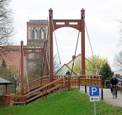 Holzbrücke / Fussgängerbrücke über das Hafenbecken in Anklam - im Hintergrund der Kirchturm der Nikolaikirche - die dreischiffige Hallenkirche der Backsteingotik stammt aus dem 14. Jahrundert.