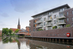Neubauten / Wohnhäuser am Hafen von Buxtehude - mehrstöckiges Wohnhaus mit Balkons - Kaimauer; im Hintegrund der Kirchturm der Sankt Petrie-Kirche.