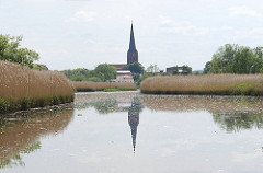 Blick vom Fluss ESTE nach Buxtehude - Kirchturm der St. Petrikirche spiegelt sich im Wasser - Schilf am Flussufer.