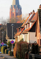 Einzelhäuser in einer Wohnstrasse in Buxtehude - im Hintergrund der Kirchturm der St. Petrikirche.