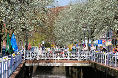 Kunstvolle Brücke über das Fleth in Buxtehude - blühende Bäume, Sonnenschein.