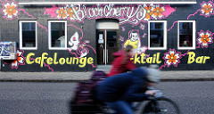Bunte Hausfassade / Graffiti - Werbung eines Cafes, Cocktail-Bar; Radfahrer auf der Strasse - Bilder aus der Stadt Uetersen, Kreis Pinneberg.