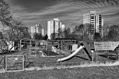Schrebergärten mit Kinderrutsche - im Hintergrund die Hochhäuser am Finkenbrook in Uetersen, Kreis Pinneberg; schwarz-weiss Fotografie.