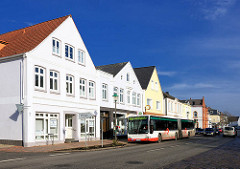 Wohnhäuser, Geschäftshäuser in der Marktstrasse von Uetersen - Bushaltestelle; weisse Fassaden, blauer Himmel.