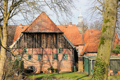 Historische Architektur auf dem Klosterhof in Uetersen - Fachwerkgebäude mit Holzfassade; im Hintergrund der Kirchturm der Klosterkirche.