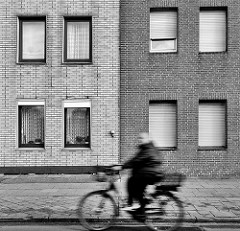 Klinkerfassade - Fenster; Radfahrer in Fahrt; Schwarz-Weiss Foto / Bilder aus der Stadt Uetersen, Kreis Pinneberg.