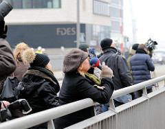 Presse und Passanten beobachten die Arbeiten an der Fassade der Elbphilharmonie von der Mahatma-Gandhi-Brücke aus.