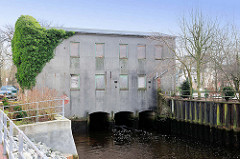 Ruine Industrieachitektur - Mühlengebäude über der Krükau in Elmshorn - die Fenster sind mit Holzplatten vernagelt.