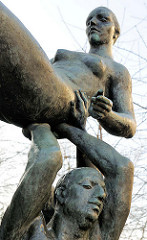 Detail Bronzestatue Der Friede bewahrt das Leben, Bildhauer Bernd Göbel, 1980. Drei nackte Männer tragen eine nackte Frau - Kunst im Öffentlichen Raum / Rostock Lichtenhagen.