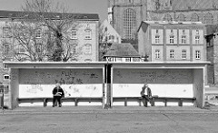 Bushaltestelle mit Graffiti - im Hintergrund Wohnhäuser und das Kirchenschiff der St. Marienkirche in der Hansestadt Stralsund.