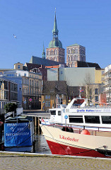 Fahrgastschiffe im Hafen der Hansestadt Stralsund - Schild Frischfisch und Räucherfisch - im Hintergrund die Kirchtürme der St. Nikolaikirche.