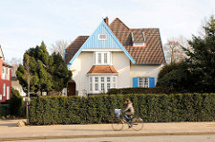 Einzelhaus, Stadtvilla - blauer Holzgiebel; Fahrradfahrerin in Fahrt.
