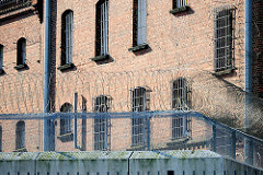 Justizvollzugsanstalt Itzehoe - rotes Backsteingebäude, erbaut 1876 - vergitterte Fenster - Mauer mit Stacheldrahtrolle, Natodraht.