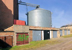 Metall-Silo im Hafen der Hansestadt Demmin - Reihe Garagen mit Holztoren.