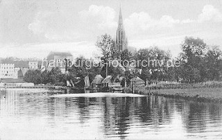 Alte Ansicht der Stadt Demmin -  Fischerhütten am Ufer dem Peene; Häuser und Kirchturm der St. Bartholomaeikirche.