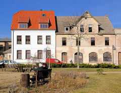 Restauriertes Wohnhaus, weisse Fassade -  rotes Ziegeldach neben einem leerstehenden verfallenene Wohnhaus - Bilder aus Bad Doberan; neu + alt.