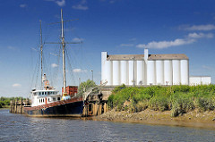 Kaimauer im Hafen von Itzehoe an der Stör - Schiff im Hafen, weisse Silos, blauer Himmel.