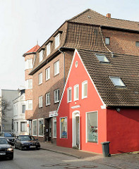 Einzelhaus mit roter Fassade neben mehrstöckiges Backsteingebäude, Wohnhaus in der Mühlenstrasse, Elmshorn.