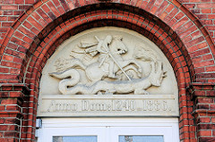 Reliefschmuck Eingang Hauptgebäude St. Jürgen Stift in Itzehoe. Sankt Jürgen ist die niederdeutsche Bezeichnung für den Heiligen St. Georg, der den Drachen besiegte.