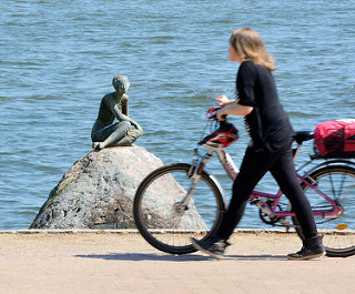 Bronzeskulptur DIE SCHAUENDE am Grossen Eutiner See; Bildhauer Karl Heinz Goedtke - eine Frau schiebt ihr Fahrrad auf dem Fussweg..