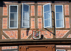 Fachwerkhaus, geöffnete Fenster - Wappen über dem Eingang.