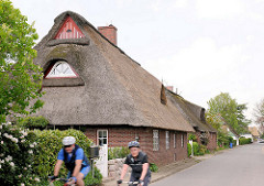 Wohnhaus mit Reetdach an der Strasse in Seestermühe - RadfahrerIn.