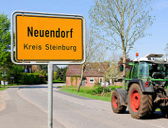 Ortsschild Neuendorf Kreis Steinburg; Trecker / Taktor auf der Strasse.