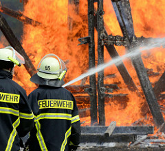 Jubiläumsfest 125 Jahre Freiwillige Feuerwehr Tangstedt - eine nachgebaute Windmühle steht in Flammen; Feuerwehrleute im Brandeinsatz, mit einem Schlauch wird Wasser in den Brandherd gespritzt.